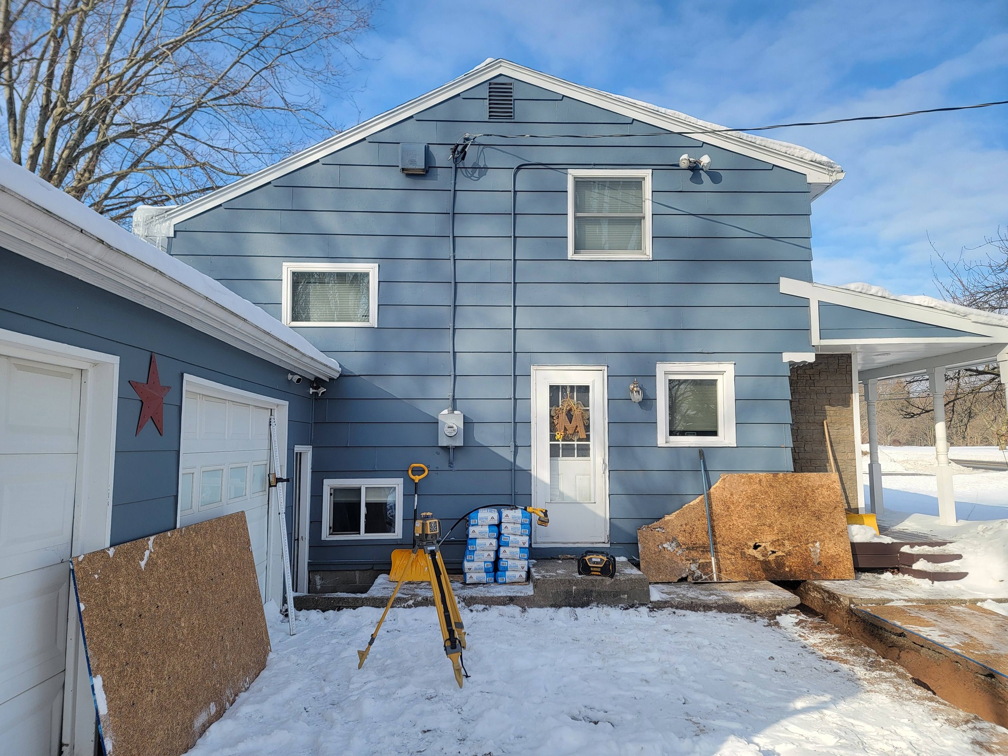 Blue-sided home exterior finish work in winter